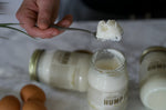 Hand holding a spoon with a scoop of coconut-based product over jars labeled 'Hump'.