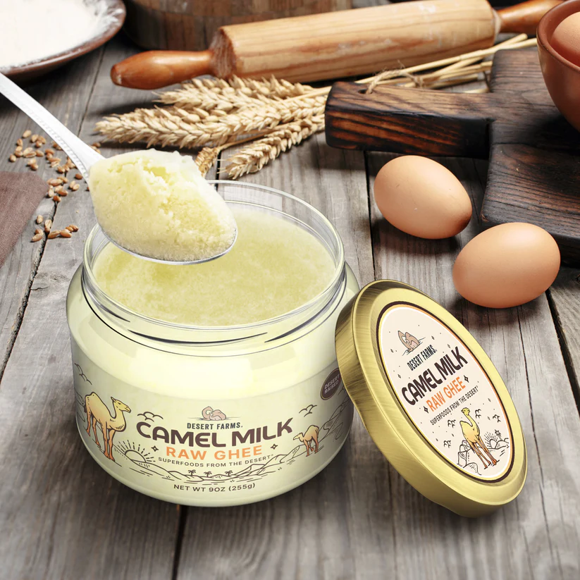 Jar of camel milk ghee with a spoonful on a wooden surface with eggs and a rolling pin.