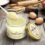 Jar of camel milk ghee with a spoonful on a wooden surface with eggs and a rolling pin.