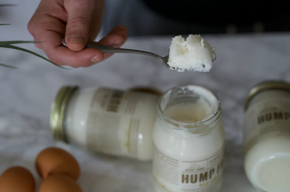 Hand holding a spoon with a scoop of coconut-based product over jars labeled 'Hump'.